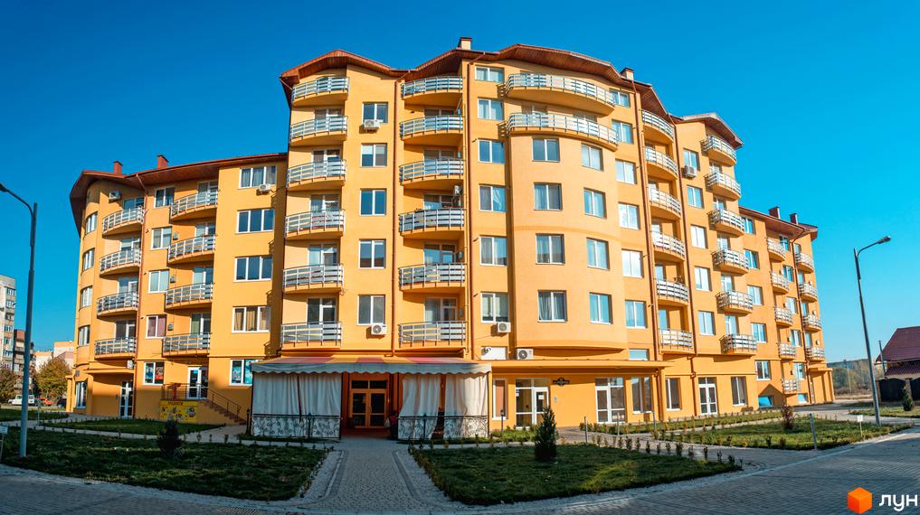 Житловий комплекс САКУРА - жовта багатоповерхівка з балконами та блакитним небом. Прибудинкова територія з доріжками та зеленню.