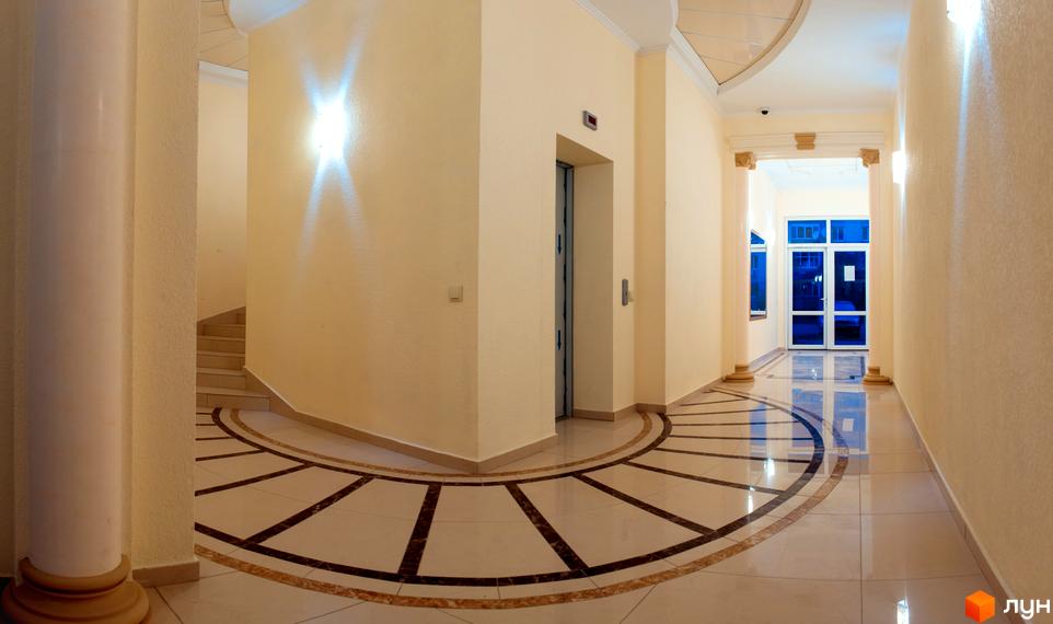 Житловий комплекс САКУРА: просторий хол з ліфтом та виходом до подвір'я з великими вікнами. Елегантний дизайн інтер'єру з мармуровою підлогою та колонами.