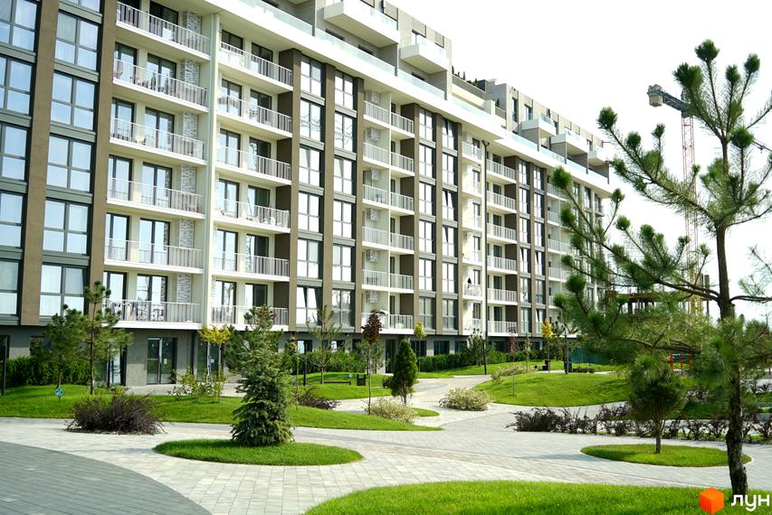 Новобудова ЖК PARK LAND з балконами та великими вікнами. Прибудинкова територія з зеленими насадженнями та доріжками.