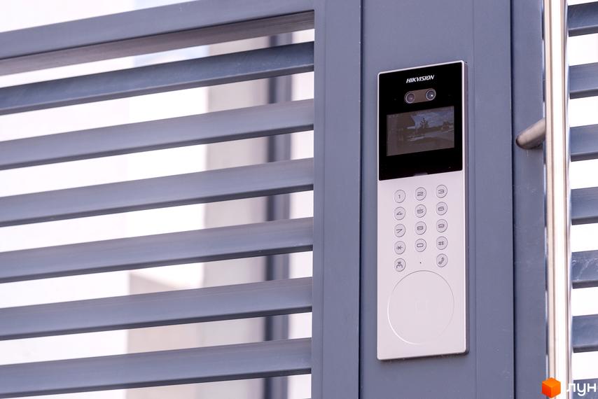 Відеодомофон на фасаді житлового комплексу SHERWOOD. Зовнішній вигляд новобудови з металевими ламелями та домофоном.