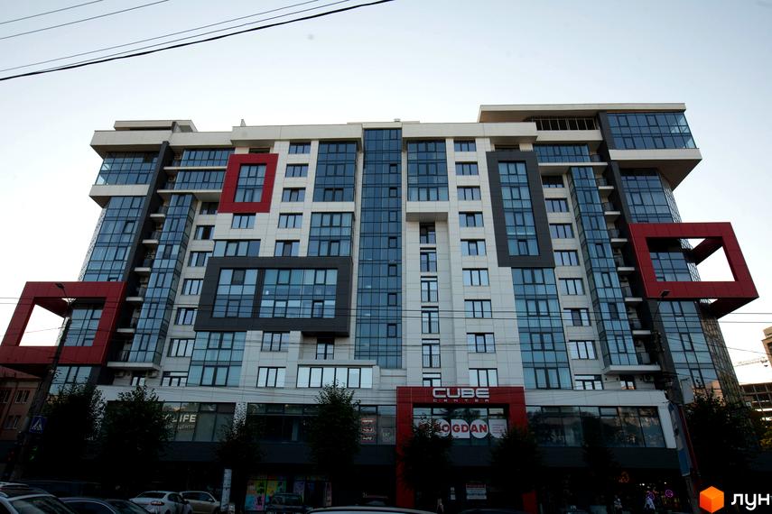 Сучасний житловий комплекс Cube House з фасадами з панорамних вікон та червоними кубічними елементами. Будинок має незвичайну архітектуру та виглядає ефектно.