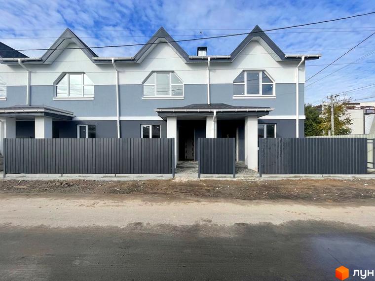 Таунхауси „Комфортне містечко“ мають світло-сірий та темно-сірий фасад, а також гострі дахи. Перед ними розташований металевий паркан темного кольору.