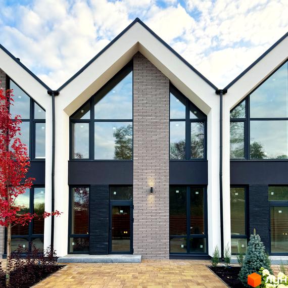 Фасад таунхаусів FreeDOM's з великими вікнами та цегляним оздобленням. Перед будинком викладена бруківкою доріжка та зелені насадження.