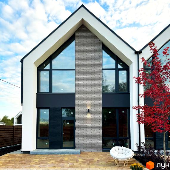 Таунхауси FreeDOM's: фасади з великими вікнами та цегляним оздобленням, перед будинком вимощена тераса з плетеними меблями.