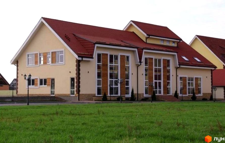 Зовнішній вигляд будинку житлового комплексу КМ Преображенський з червоною покрівлею. Прибудинкова територія з зеленим газоном та ліхтарями.