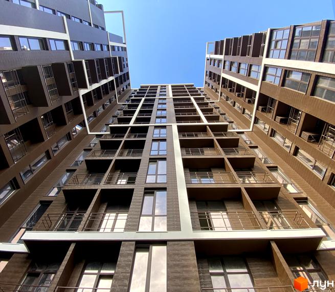 Житловий комплекс Пространство на Гераневій. Високі будинки з великою кількістю вікон та балконів на фоні блакитного неба.