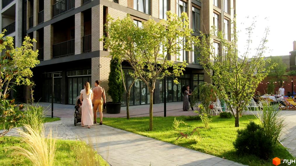 Вигляд фасаду будинку та прибудинкової території Житлового комплексу Пространство на Донського. Подвір'я з газоном та пішохідною зоною.