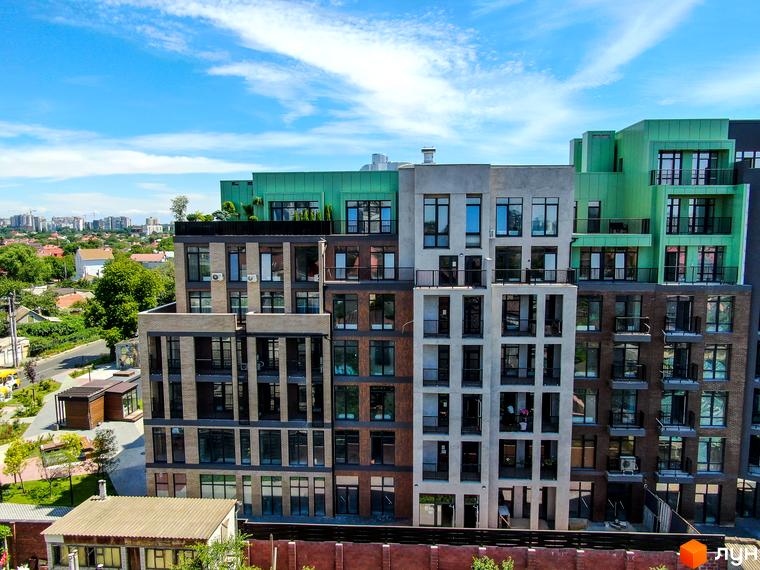 Фото фасаду та прибудинкової території Житлового комплексу Пространство на Донського. Багатоповерхова будівля з великими вікнами та балконами.