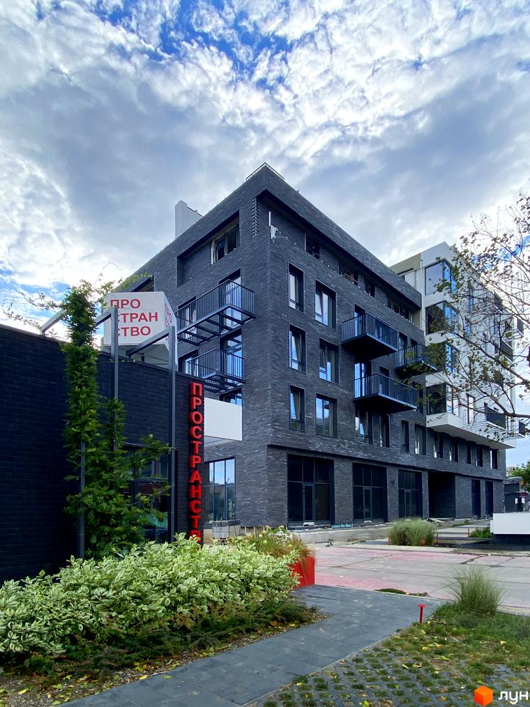 Будинок житлового комплексу Пространство на 9-й Фонтана з чорною цегляною облицовкою та балконами. Навколо будинку зелені насадження та доріжки.