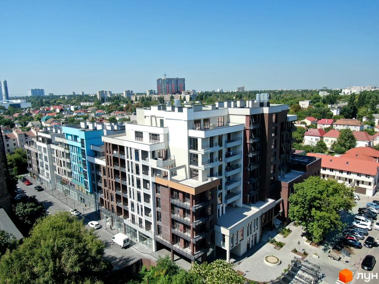 Простір на Недєліна – це сучасний житловий комплекс з багатоповерховими будинками та доглянутою прибудинковою територією. На фото видно фасади будівель, балкони та паркувальні місця біля будинку.