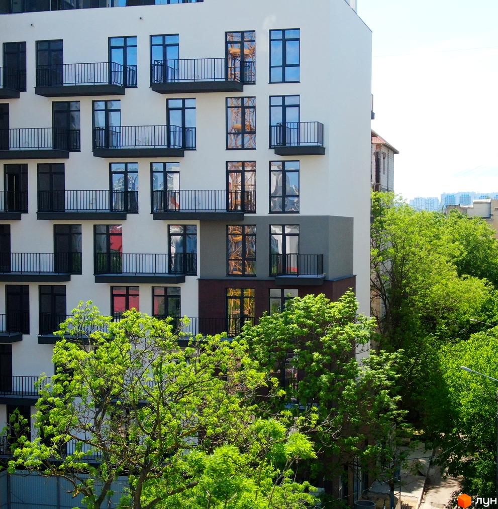 Фасад новобудови Пространство на Педагогической з численними балконами та вікнами. Навколо будівлі зелені дерева.