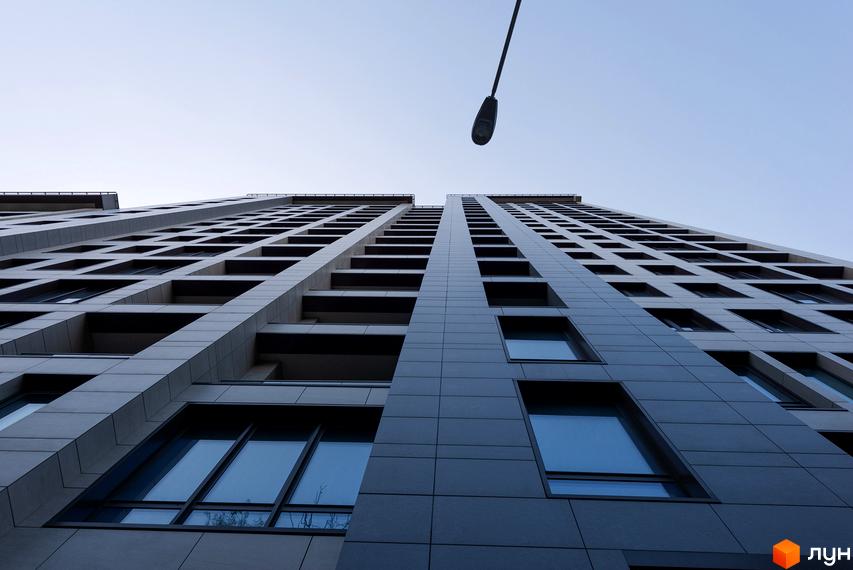Житловий комплекс Crystal Park Tower з сірим фасадом та численними вікнами, що тягнуться вгору до неба.
