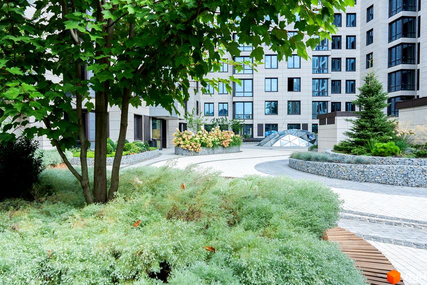 Житловий комплекс Crystal Park Tower з доглянутою прибудинковою територією, що включає зелені насадження та зону відпочинку.