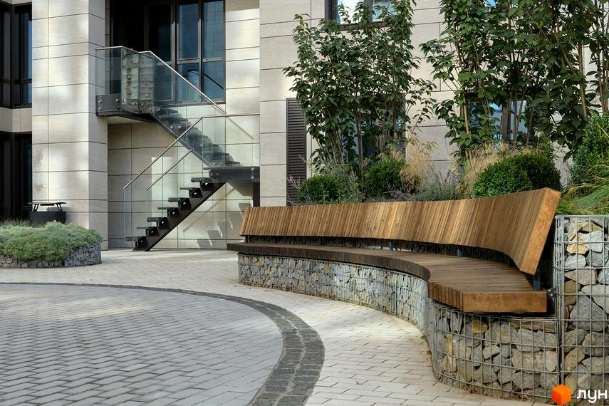 Житловий комплекс Crystal Park Tower з оновленою прибудинковою територією, що включає лаунж-зону з дерев'яною лавкою та озеленення.