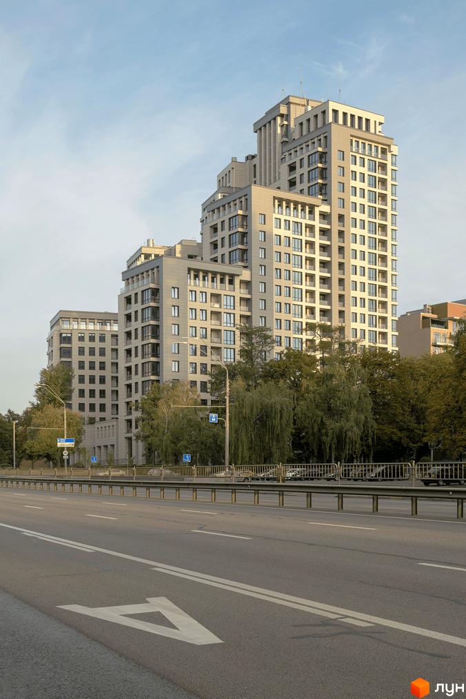 Житловий комплекс Crystal Park Tower – це багатоповерхова будівля з терасами та великими вікнами, розташована біля дороги та зелених дерев.