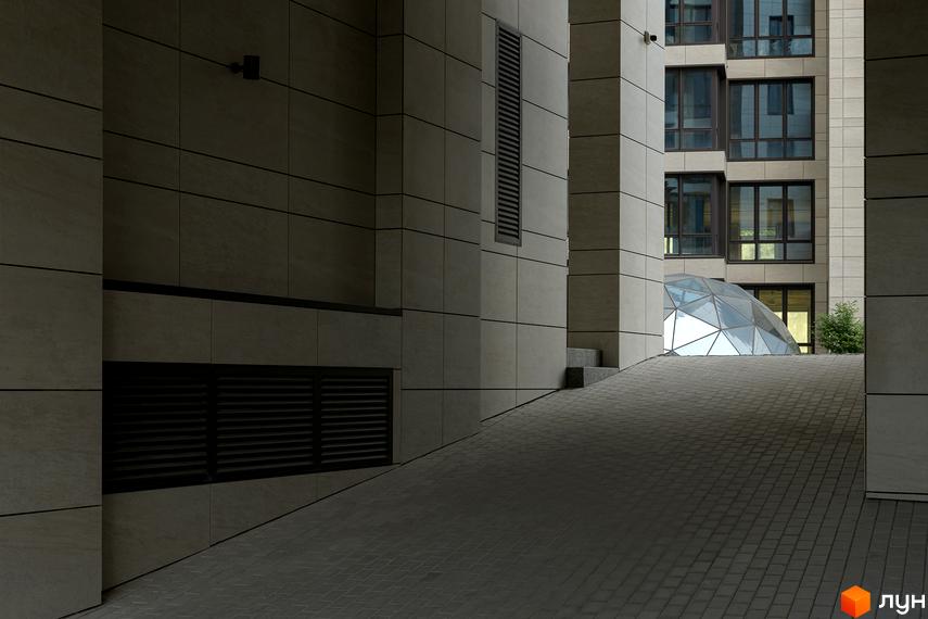 Зовнішній вигляд новобудови Crystal Park Tower з панорамними вікнами та скляним куполом. Територія навколо комплексу з бруківкою та пандусом.