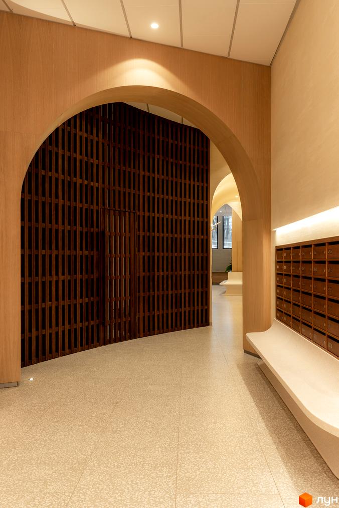 Інтер'єр житлового комплексу Crystal Park Tower з арковим проходом, дерев'яними елементами та поштовими скриньками. Сучасний дизайн входу в новобудову.