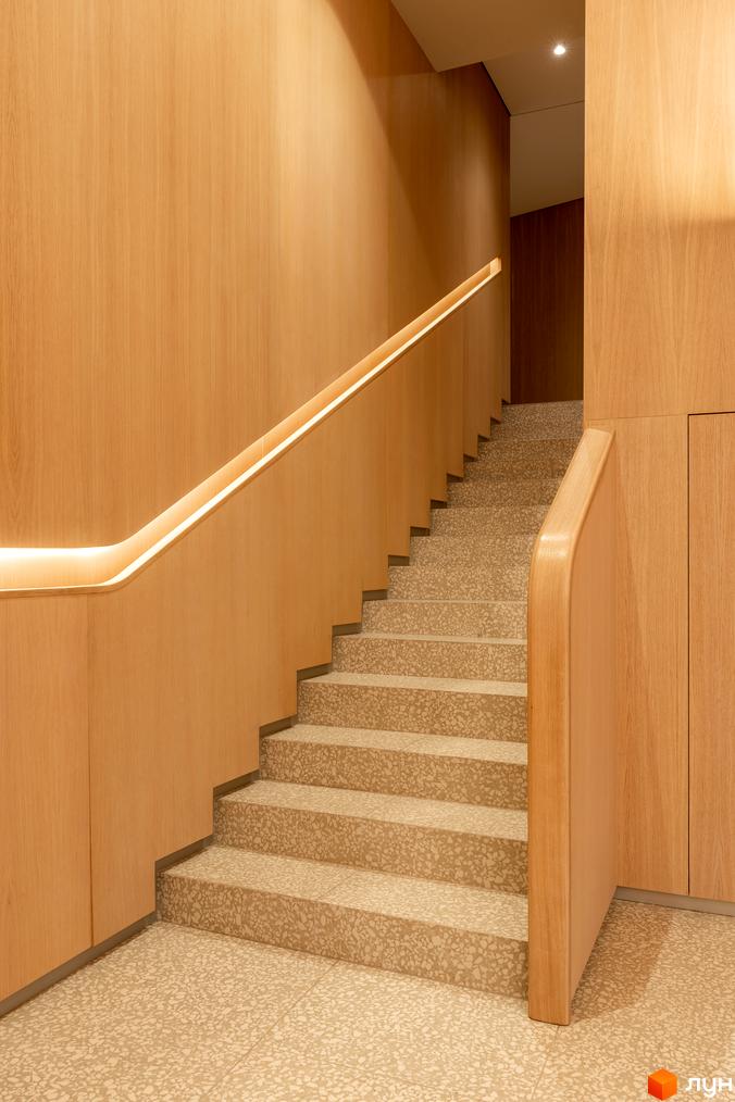 Інтер'єр сходів у ЖК Crystal Park Tower з дерев'яними панелями та підсвічуванням. Теразна плитка на сходах та підлозі.