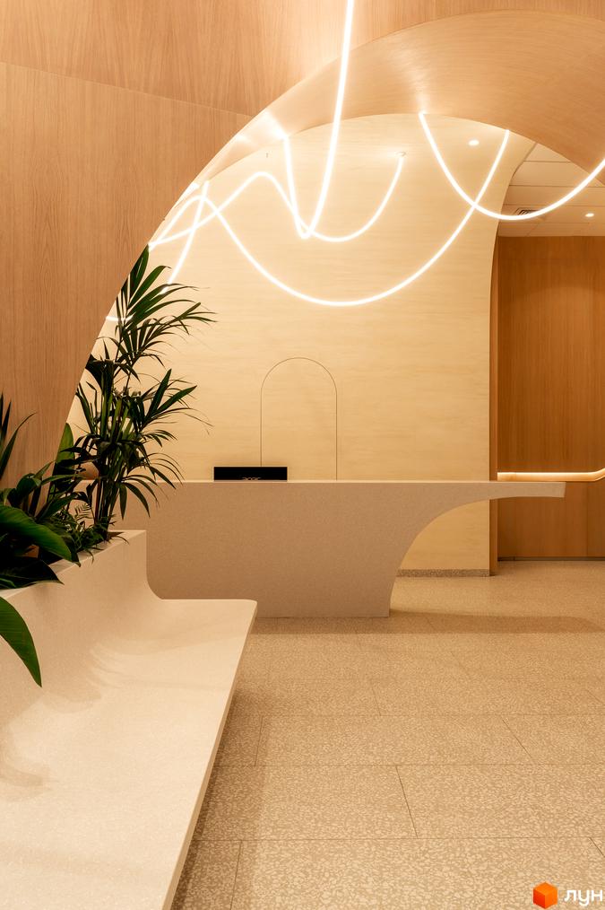 Інтер'єр ЖК Crystal Park Tower з ресепшн, лаунж-зоною та рослинами. Сучасний дизайн з вигнутими лініями та дерев'яними елементами.