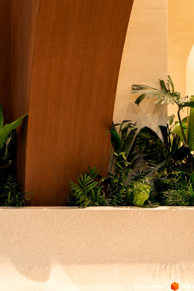 Житловий комплекс Crystal Park Tower з дерев'яними та світлими панелями, оточений зеленню та рослинами. Тераса з кам'яною поверхнею та тінями від рослин.