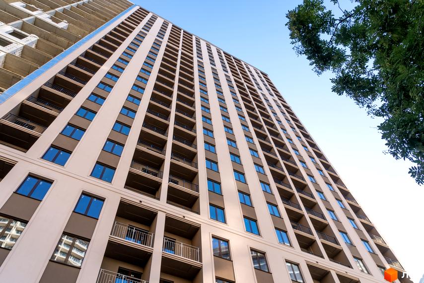 Зовнішній вигляд новобудови ЖК Еллада з численними балконами та вікнами на фоні блакитного неба. Будівельний проєкт з високою поверховістю.