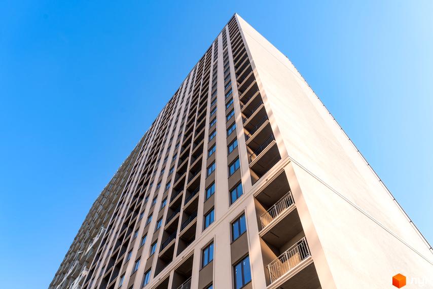 Фасад житлового комплексу Еллада з численними балконами та вікнами на тлі блакитного неба. Зовнішній вигляд новобудови.