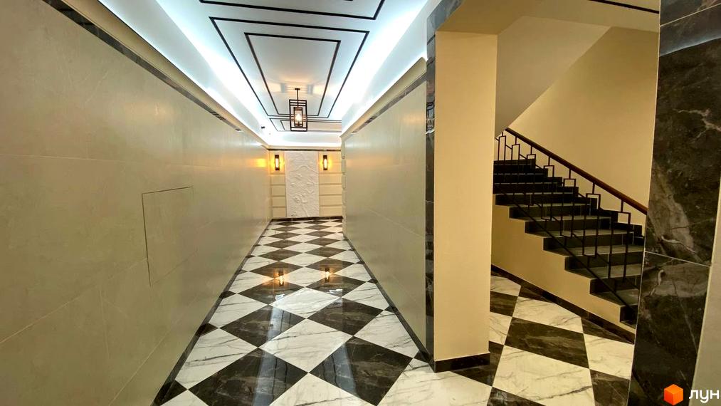 Інтер'єр холу в Житловому комплексі Бургундія з чорно-білою плиткою на підлозі та сходами на другий поверх.