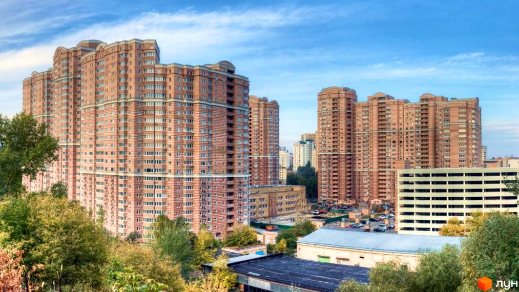 Житловий комплекс Голосіїво складається з високих будівель з цегляними фасадами та численними вікнами. Навколо комплексу багато зелених дерев.