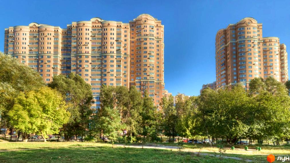 Житловий комплекс Голосіїво: високі житлові будинки світло-коричневого кольору з округлими фасадами, оточені зеленим парком з деревами.