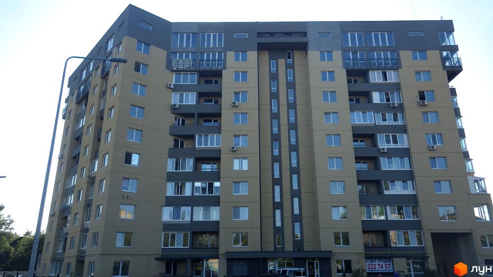 Новобудова на вул. Авіаційна (Туполєва), 17к: багатоповерховий будинок з бежево-сірим фасадом, балконами та великими вікнами. Поруч видно вуличний ліхтар.
