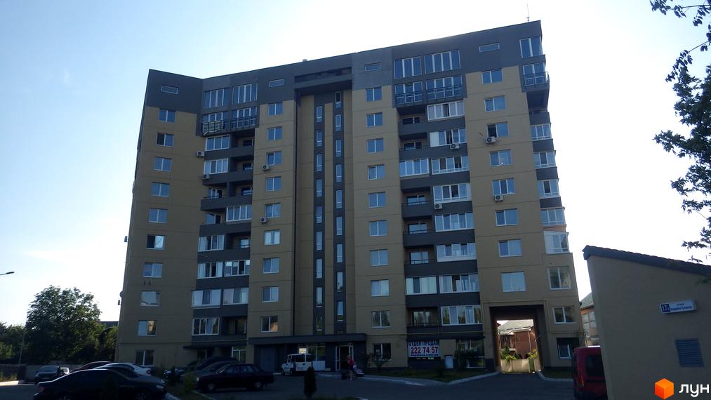 Житловий комплекс на вул. Авіаційна, 17к з сучасним фасадом та прибудинковою територією. На фото видно автомобілі та зелень.