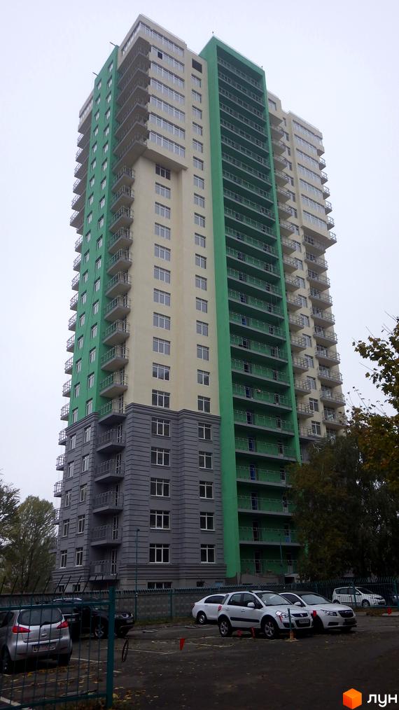 Багатоповерховий будинок Житлового комплексу Столичні каштани з бежевими, зеленими та сірими фасадами, балконами та вікнами. На передньому плані видно парковку з автомобілями та дерева.