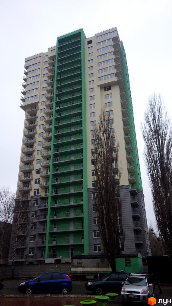 Житловий комплекс Столичні каштани: висотна будівля з бежевим та яскраво-зеленим фасадом, обладнана балконами. На передньому плані видно прибудинкову територію з автомобілями та деревами.
