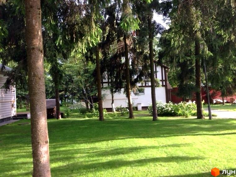 Зовнішній вигляд будинку в КМ Иволга, оточеного зеленими деревами та доглянутою прибудинковою територією.