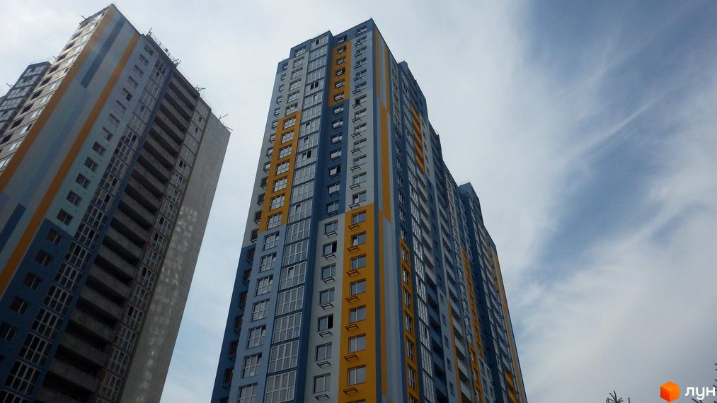 Новобудова ЖК Welcome Home на Ревуцького з блакитно-жовтими фасадами. Висотні будинки з панорамними вікнами на тлі хмарного неба.