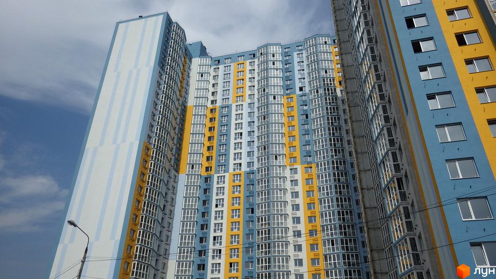 Зовнішній вигляд новобудови ЖК Welcome Home на Ревуцького: багатоповерхові будинки з яскравим фасадом у блакитних, жовтих та білих кольорах. Вікна великі, панорамні, з білими рамами.