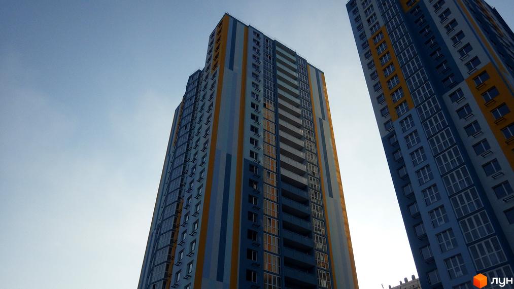 Високоповерховий житловий комплекс Welcome Home на Ревуцького з яскравим фасадом у синьо-жовтих кольорах. Сучасна архітектура та багато вікон.