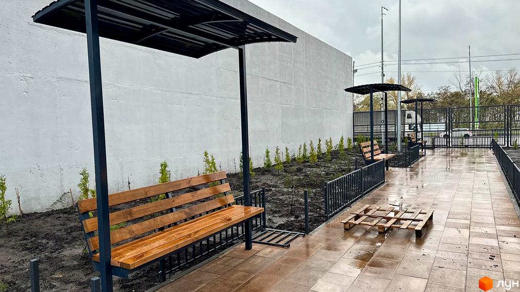 Житловий комплекс Берег Дніпра: зона відпочинку з лавками під навісами та доглянутою прибудинковою територією.