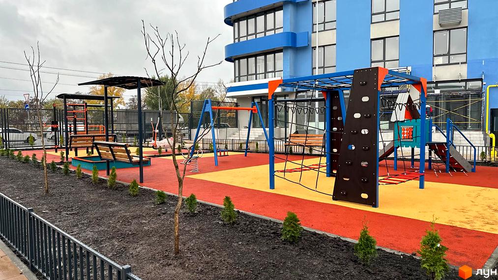 Зображення дитячого майданчика біля Новобудови Берег Дніпра. На фото видно ігровий комплекс, гірки, гойдалки та пісочницю.