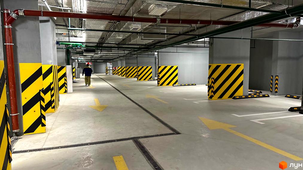 Паркінг в ЖК Берег Дніпра з жовто-чорними обмежувачами та стрілками напрямку руху. Ознайомлення з інфраструктурою житлового комплексу.