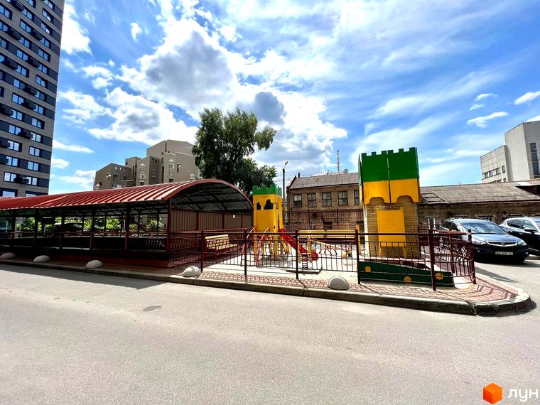 Житловий комплекс на вул. Антоновича, 72 з дитячим майданчиком та прибудинковою територією. Вид на сучасну архітектуру та зелені насадження.