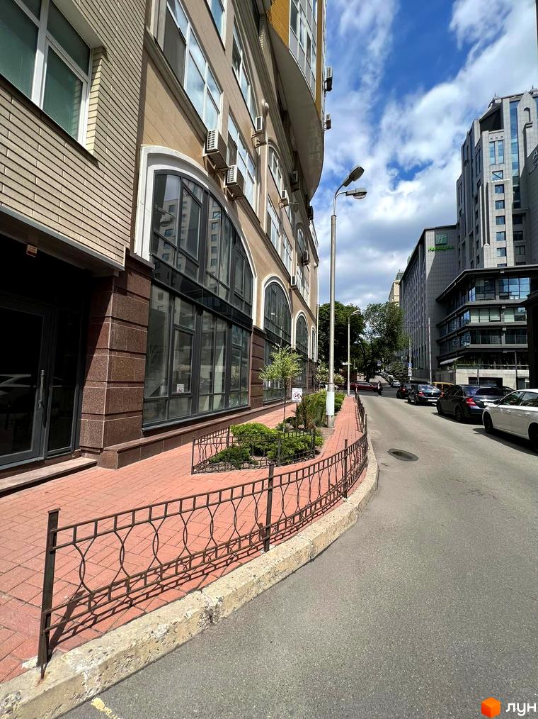 Зовнішній вигляд житлового комплексу на вул. Антоновича, 72 з великими вікнами та прибудинковою територією з зеленими насадженнями.