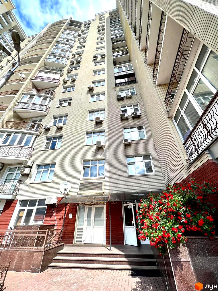 Житловий комплекс на вул. Антоновича, 72. Вид на фасад будинку та прибудинкову територію з квітами.