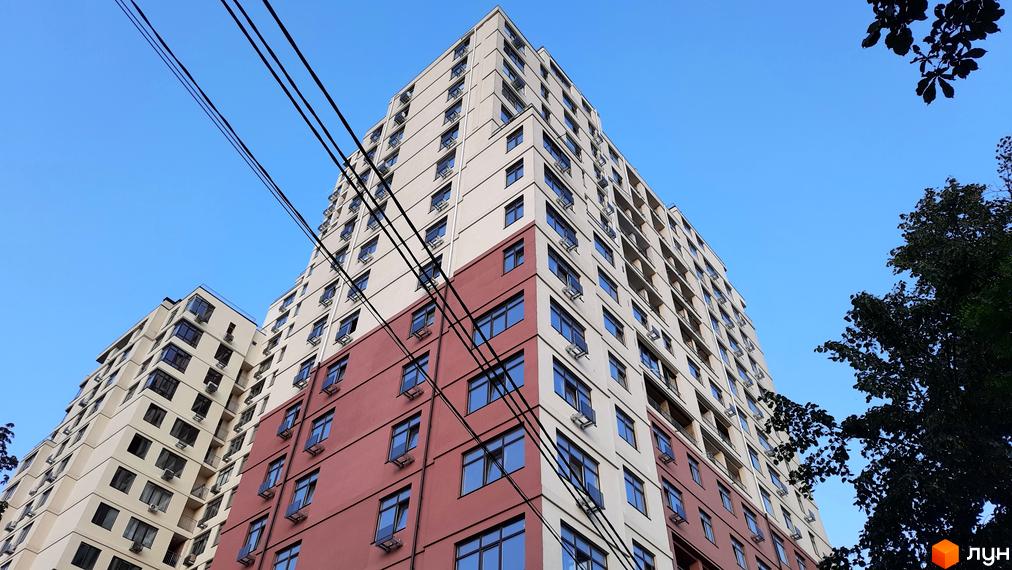 Житловий комплекс Henesi House з багатоповерховою будівлею та сучасними вікнами, оточений зеленими насадженнями.