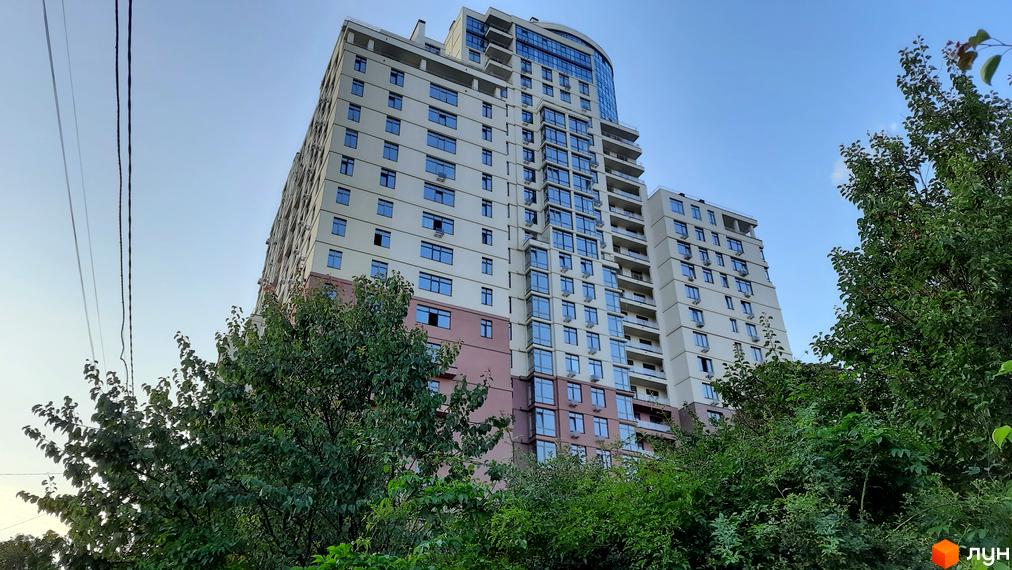 Житловий комплекс Henesi House з сучасним фасадом, оточений зеленою територією та деревами.