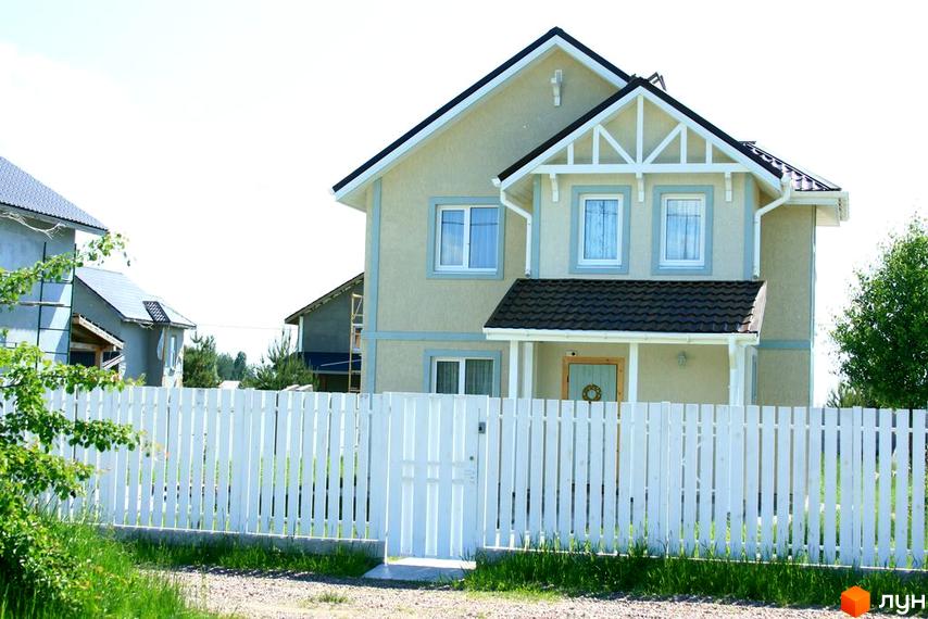 Зображення будинку в Котеджному містечку Лісна Пісня. Двоповерховий будинок з білим парканом та зеленою територією.