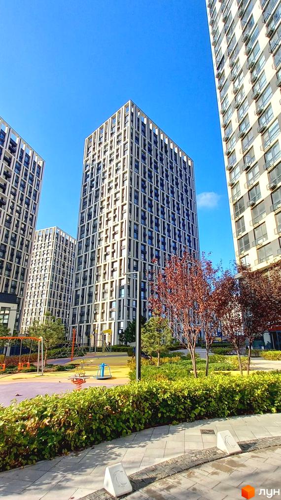 Житловий комплекс Славутич: висотні будинки з типовим фасадом та дитячий майданчик з гойдалками та гірками.