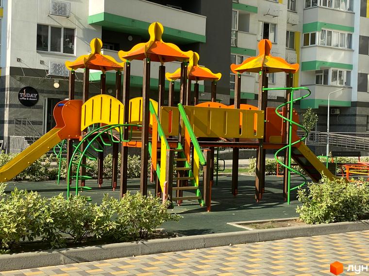 Дитячий майданчик у житловому комплексі Харківський. Яскравий ігровий комплекс з гірками та лазалками на зеленій території біля новобудови.