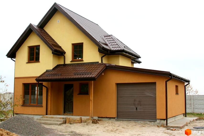 Зображення двоповерхового будинку в Котеджному містечку Лісна Пісня з коричневим дахом та гаражем. На передньому плані видно будівельні матеріали.