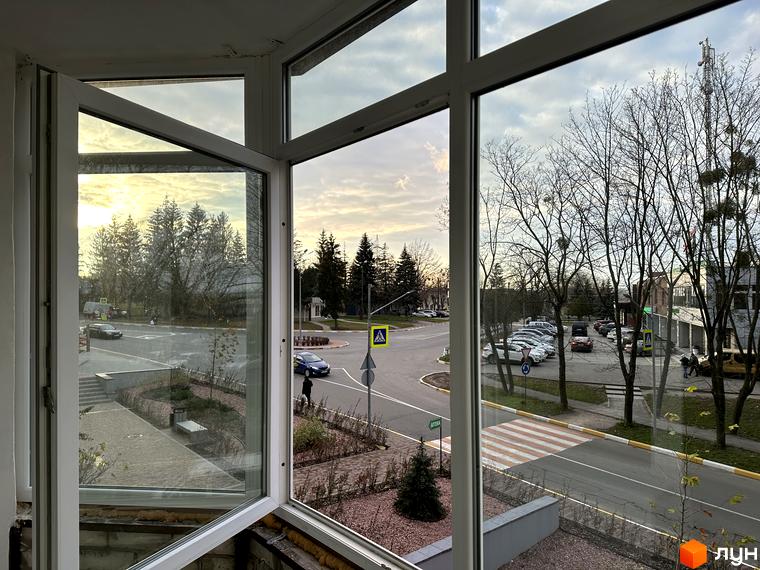 Вид з вікна на міський пейзаж з дорогою та деревами. ЖК Всі Свої - це новий житловий комплекс з розвиненою інфраструктурою.